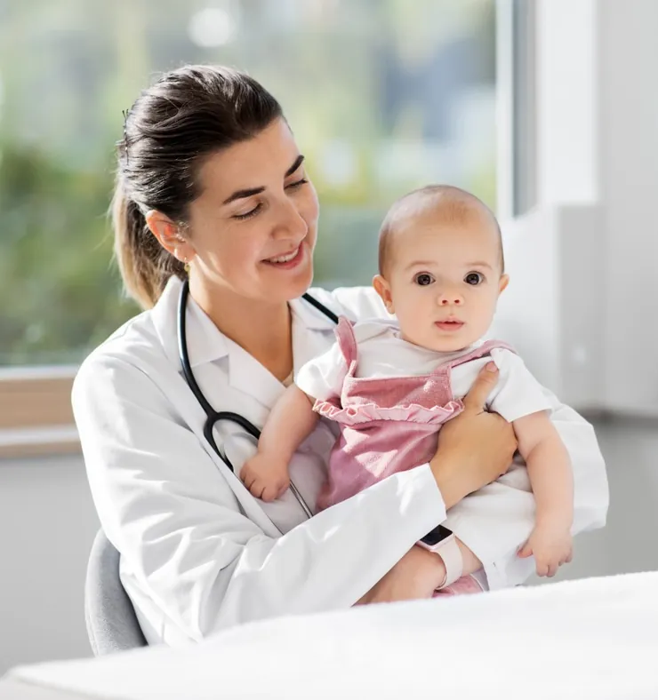 A smiling doctor holding a baby