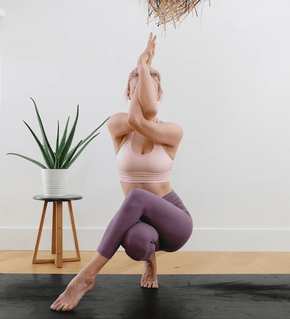 A woman holding a balanced yoga pose with her arms raised