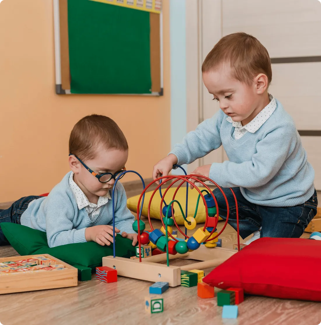 Two children playing with a bead maze