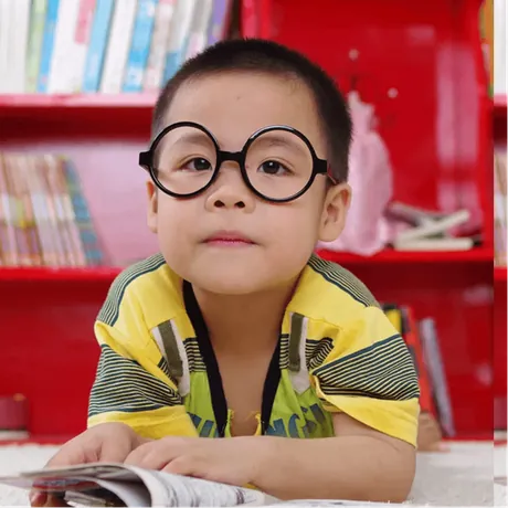 A boy in round glasses reading a book