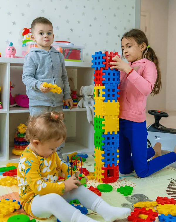 Children building a tall tower of plastic blocks