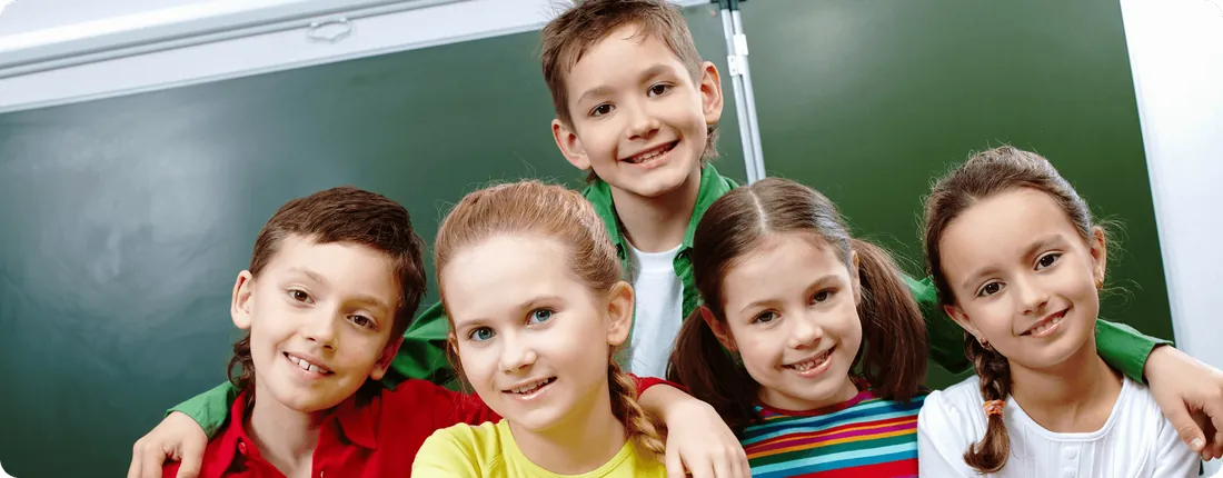 A group of smiling children in front of a chalkboard