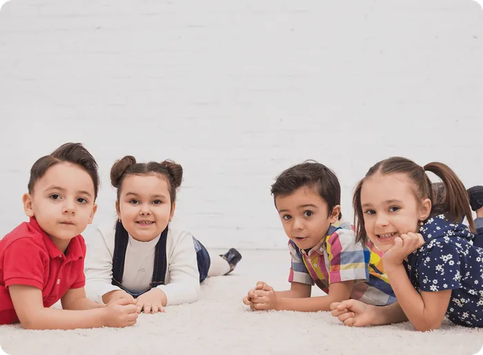 Four children lying on the floor, smiling at the camera