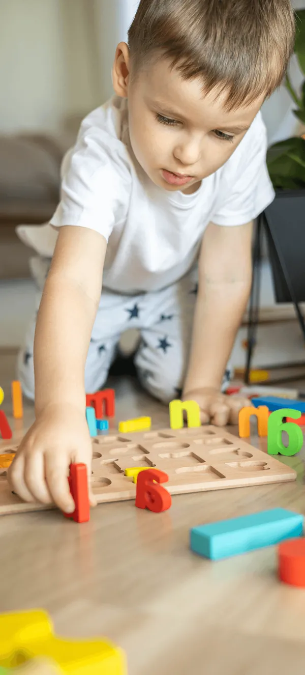 A boy building a wooden block tower on the floor