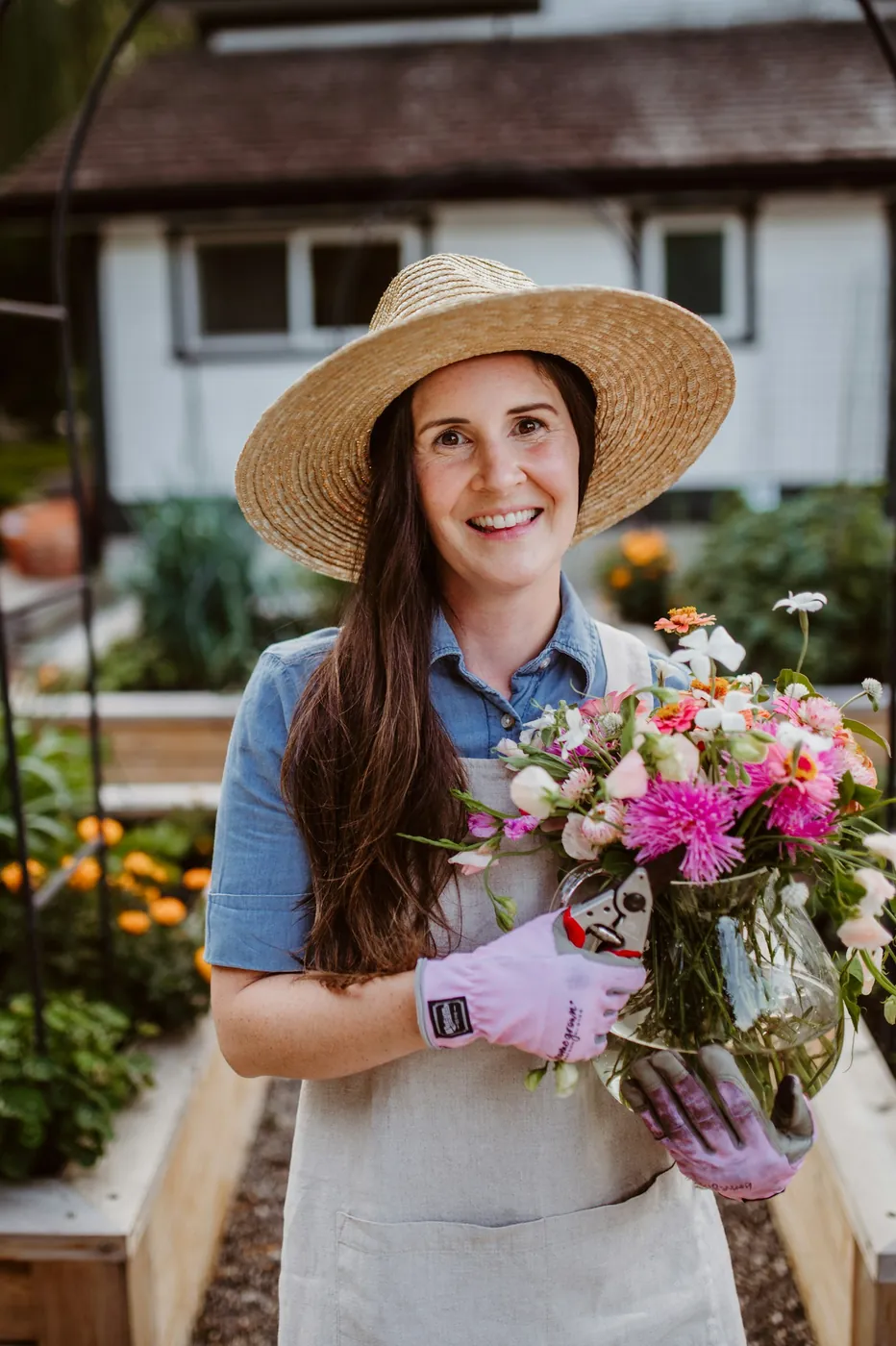 A gardener in a straw hat holding a bunch of fresh flowers