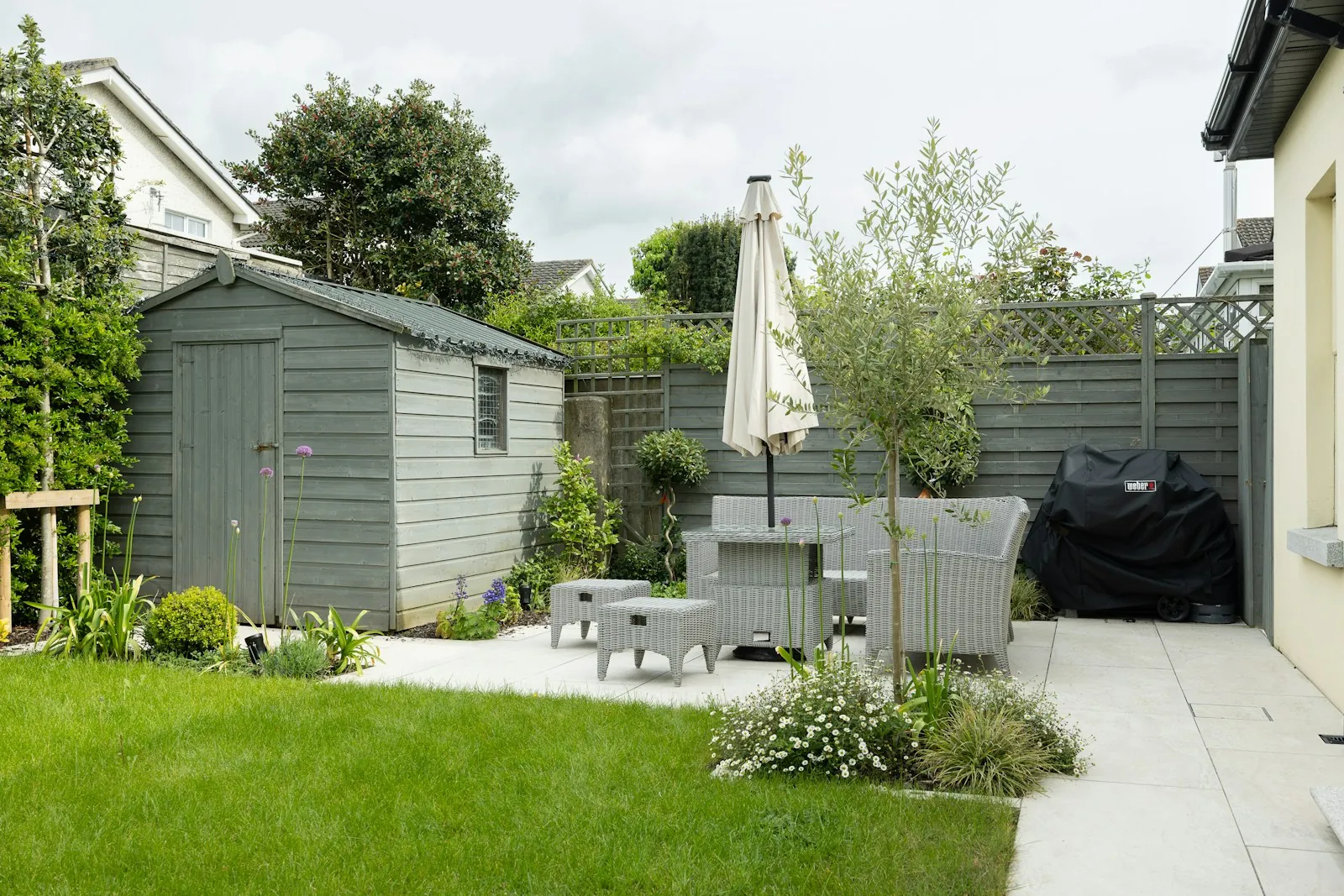 A small garden with a shed, a terrace and a parasol