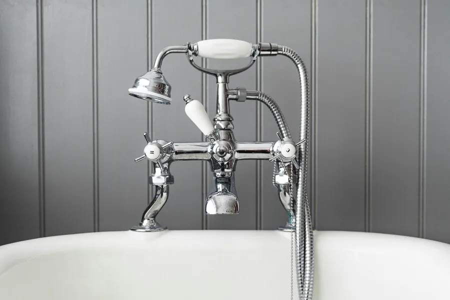 A chrome bath mixer tap on a white bathtub