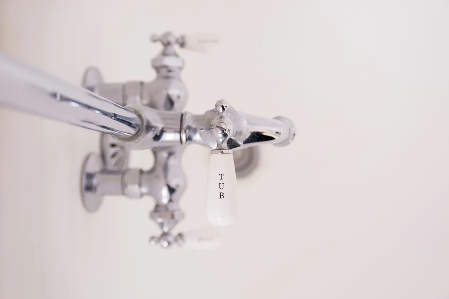 A chrome wall tap above a basin