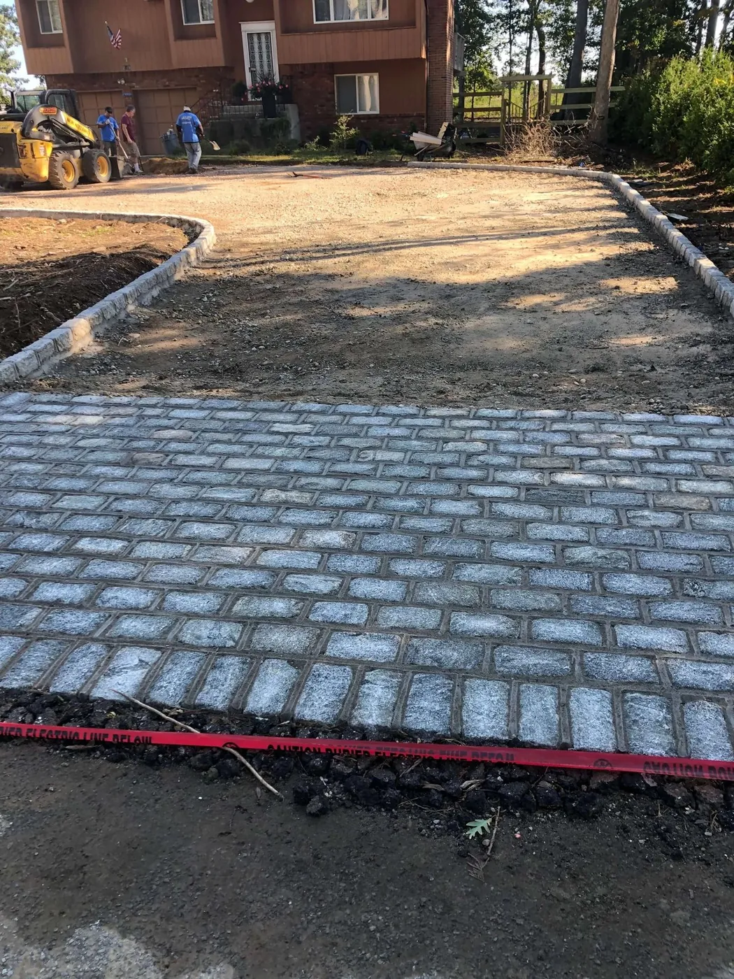 A cobblestone driveway apron with granite curb edging set ahead of the base preparation