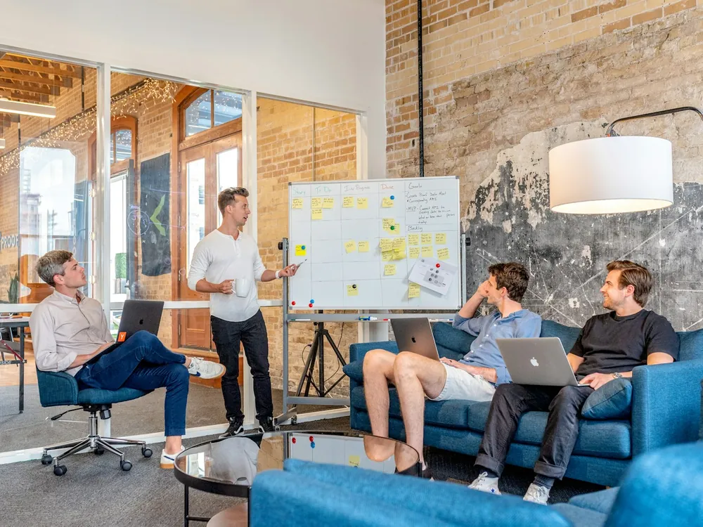 A team working through a whiteboard of notes in a loft office