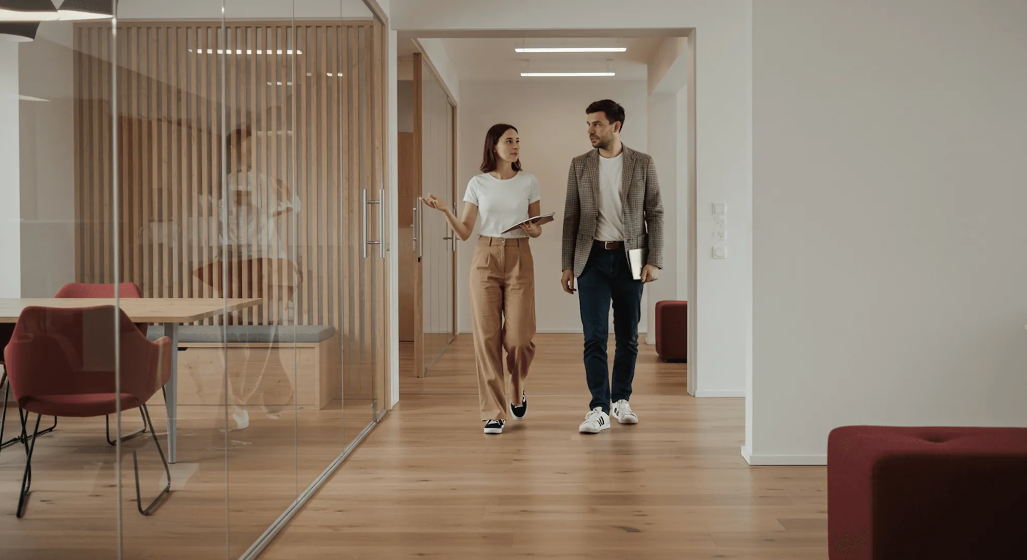 Two colleagues walking and talking along an office corridor