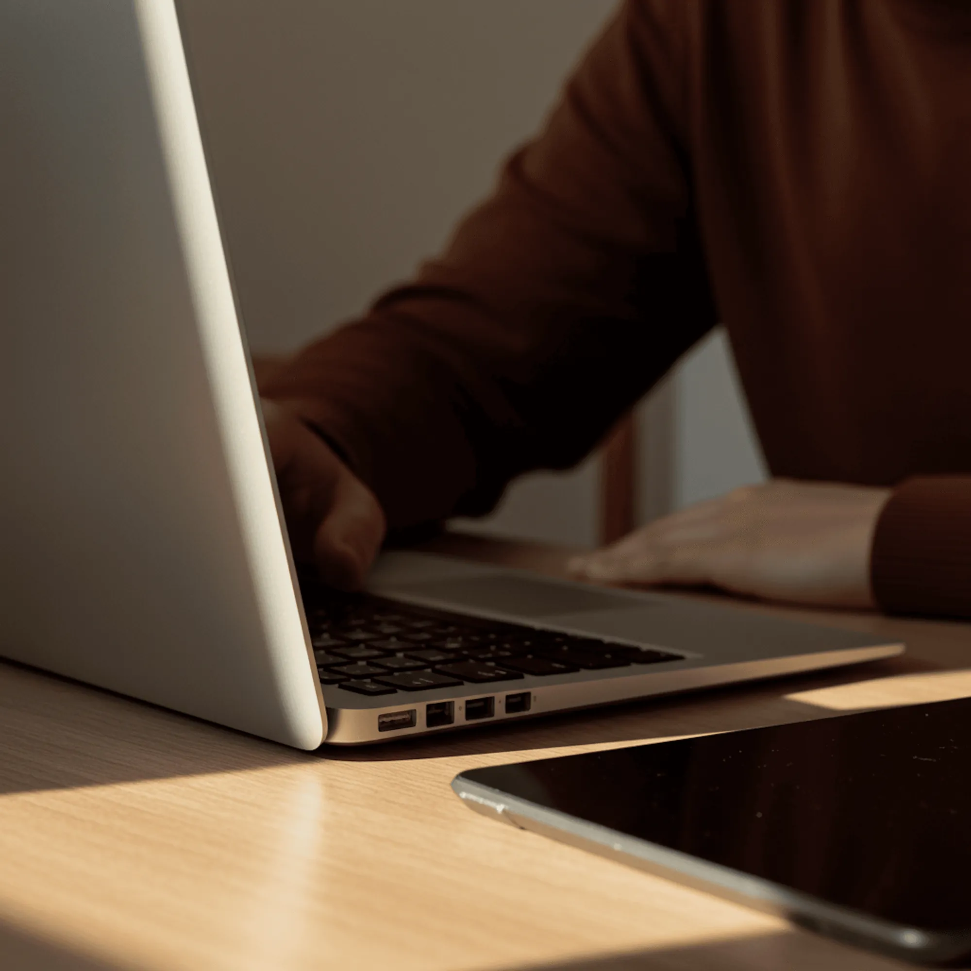Hands on a laptop on a wooden desk