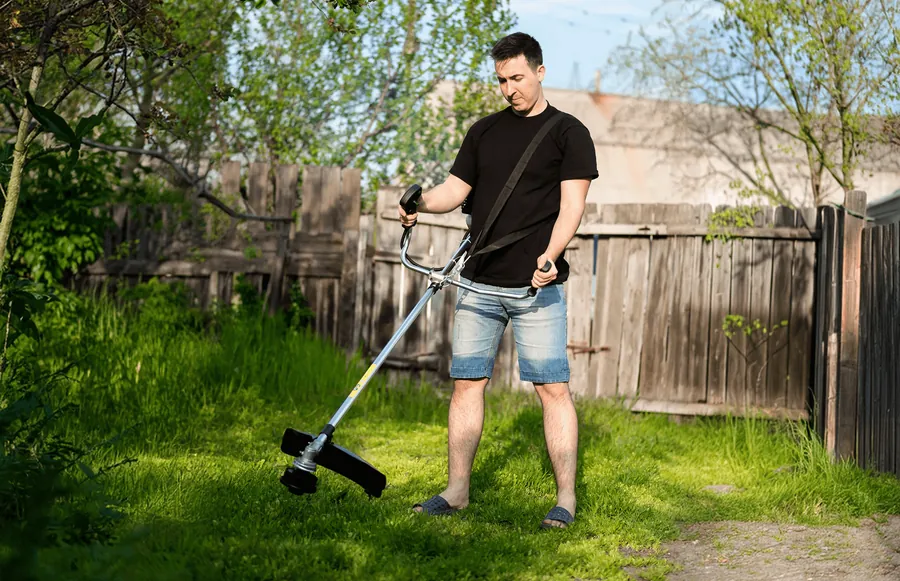 A man trimming the lawn with a string trimmer