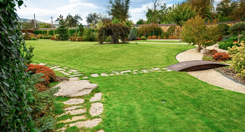 A lawn with stepping stones and a small bridge, after