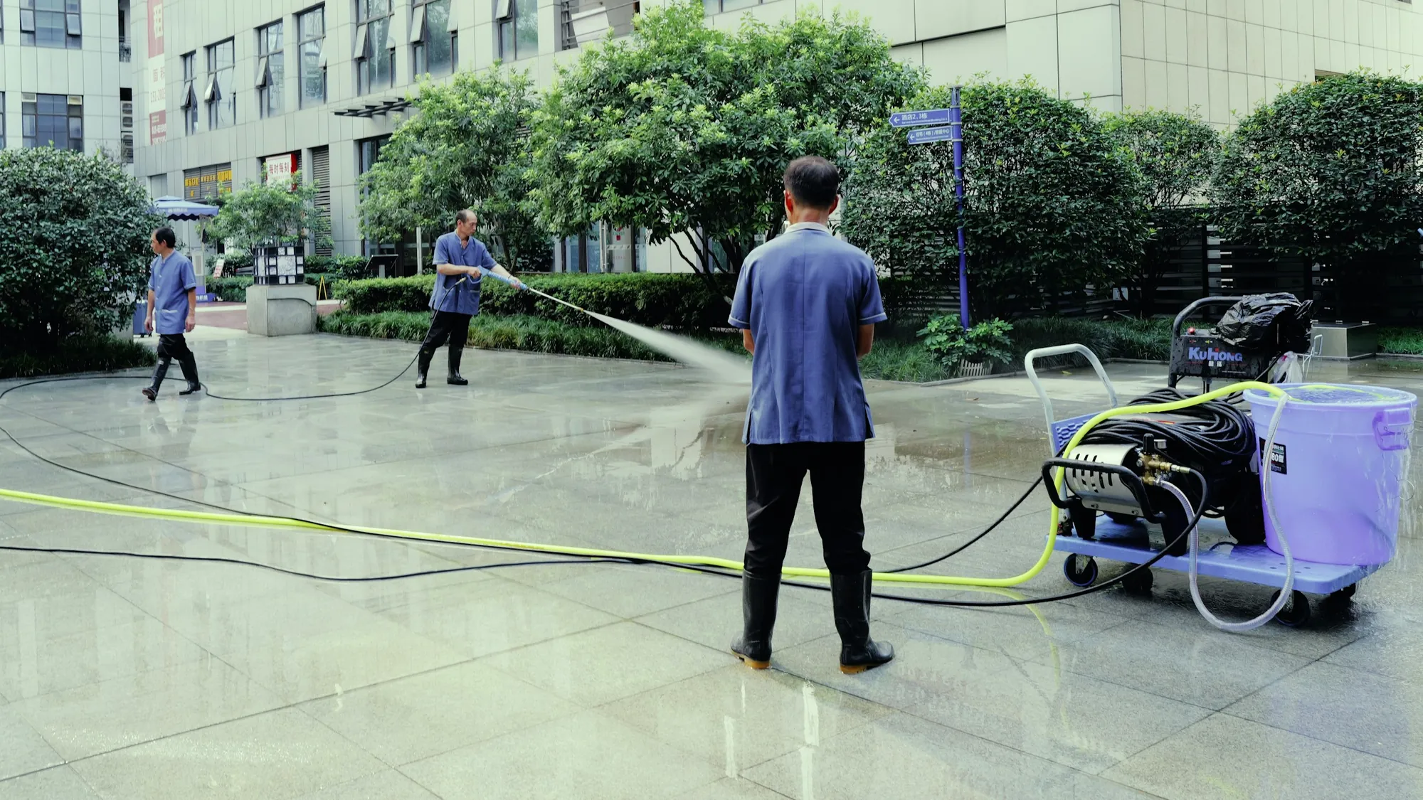 Technicians pressure washing a paved courtyard