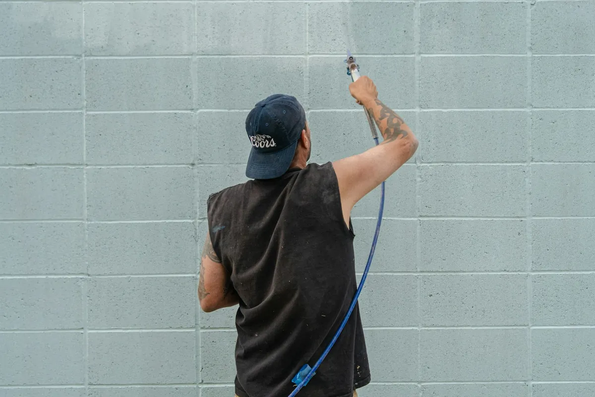 Technician washing an exterior wall with a pressure lance