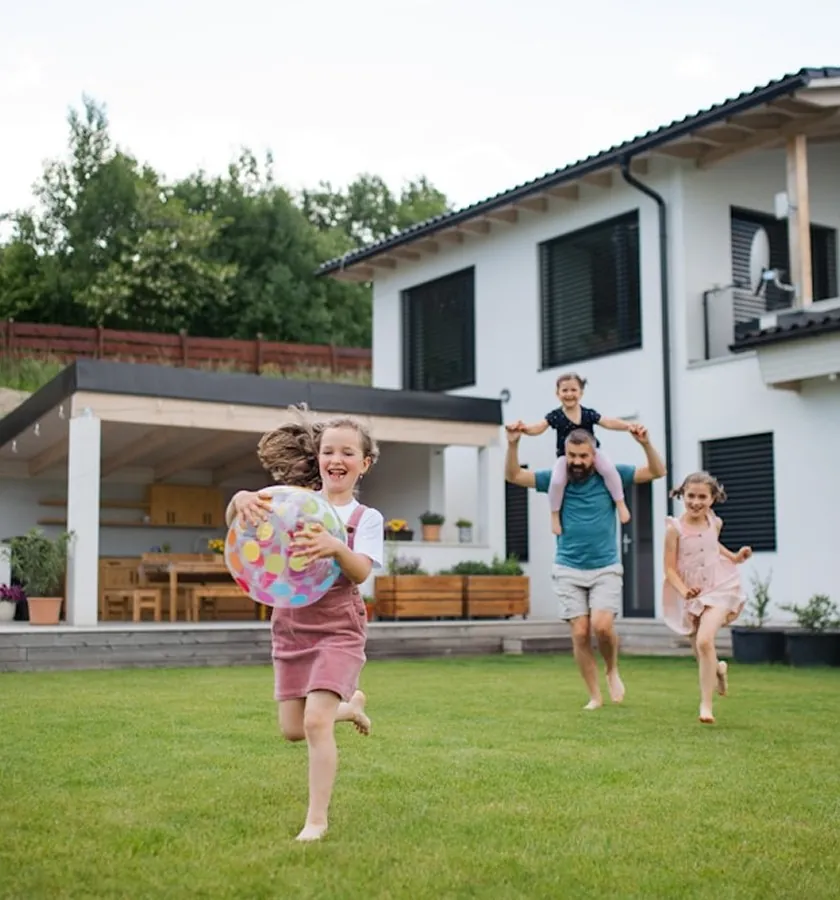 A family playing on the lawn of a white house