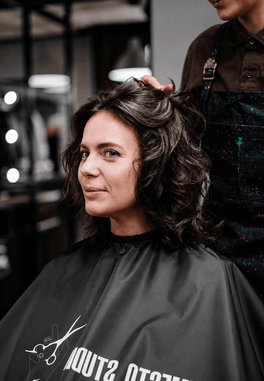 A stylist styling a client's curls in the salon