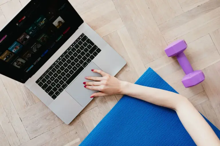 A laptop and a dumbbell on an exercise mat