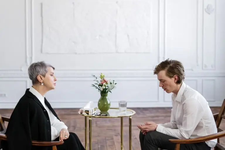 Two people talking at a table in a bright room
