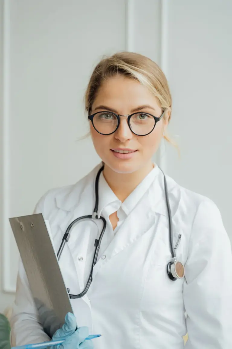 A doctor in glasses holding a laptop