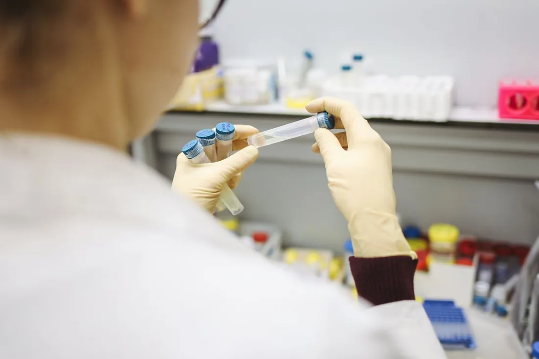 Gloved hands holding a test tube in a lab