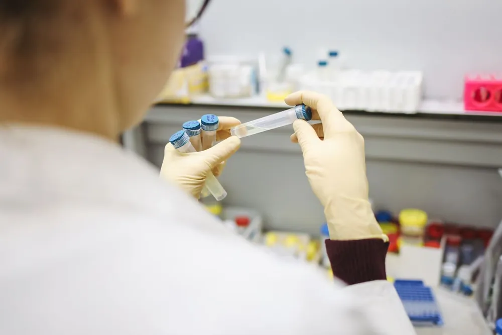 A gloved hand holding blood sample tubes