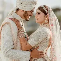 The couple at their reception in cream and gold outfits