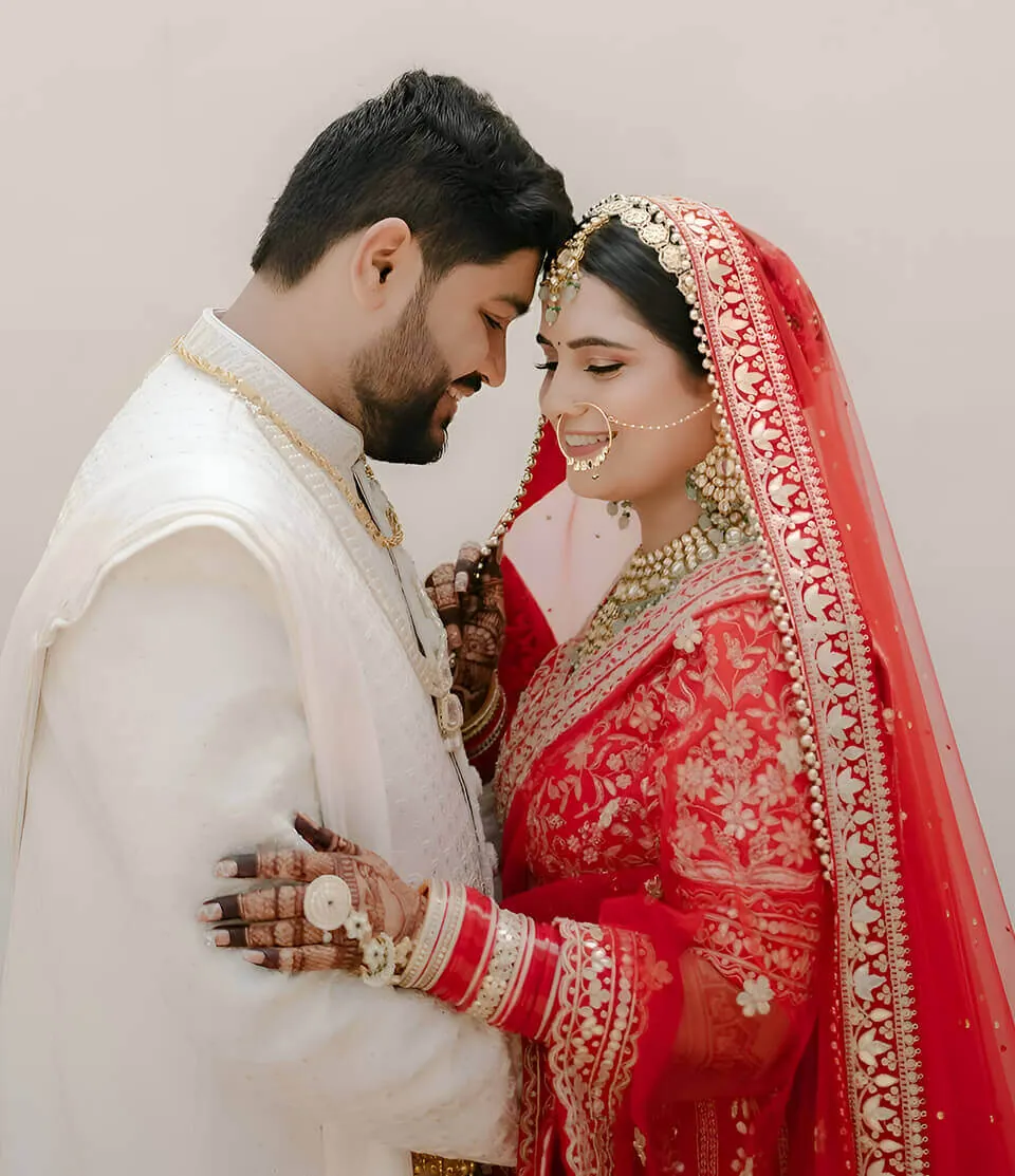 The bride and groom standing forehead to forehead in traditional wedding dress