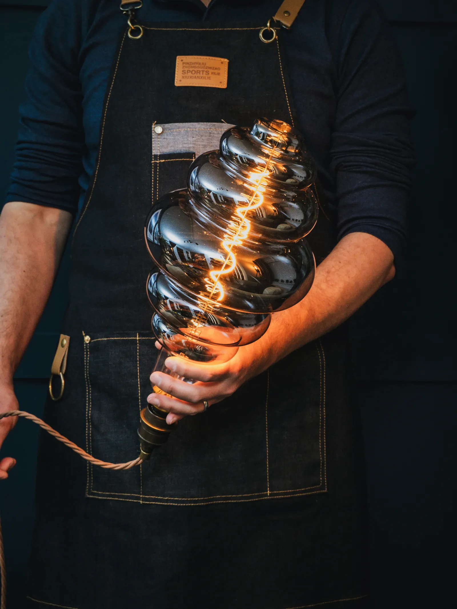 Hands holding a large spiral filament light bulb