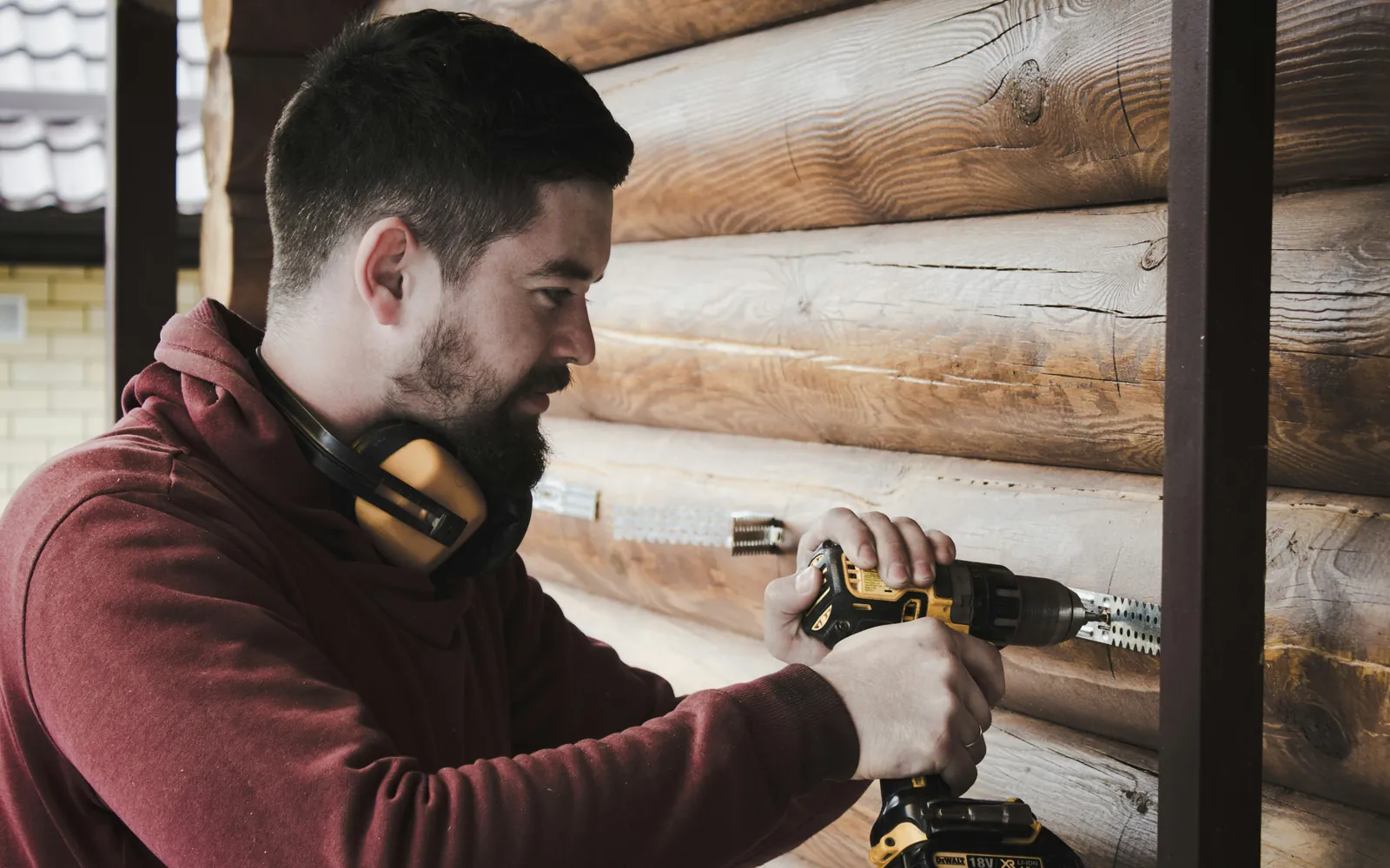 An electrician drilling into a log wall