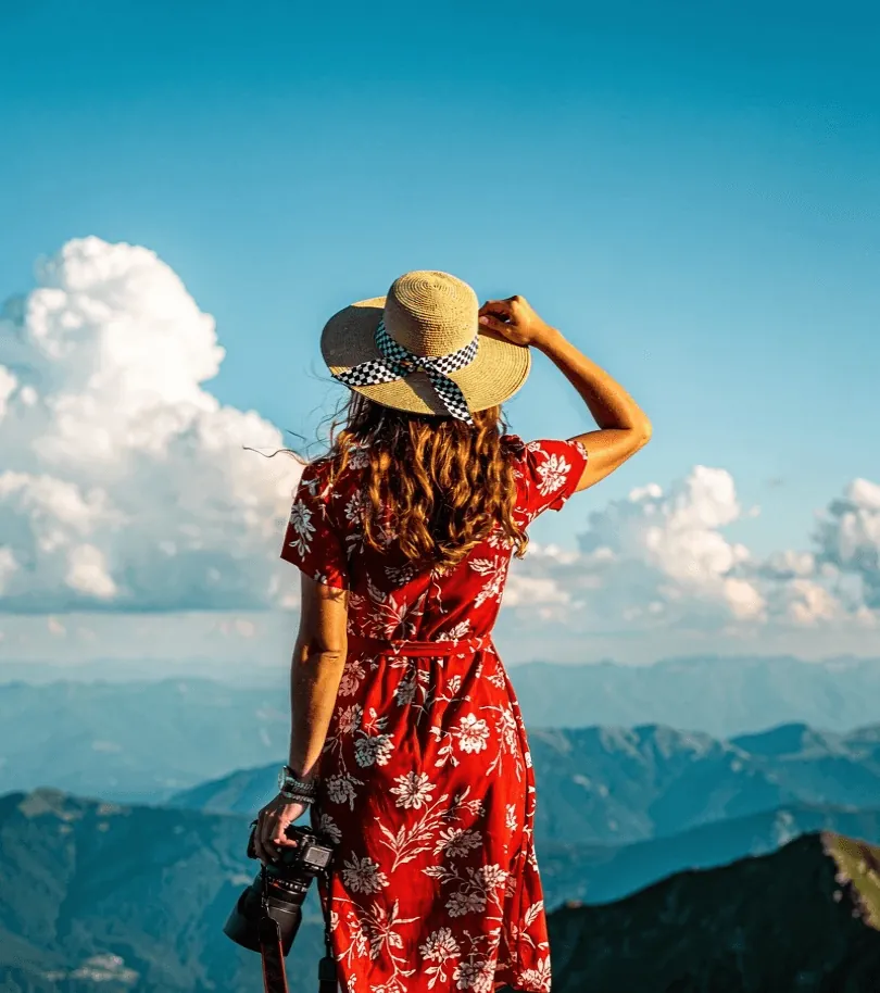 A woman in a red dress and sun hat above the clouds