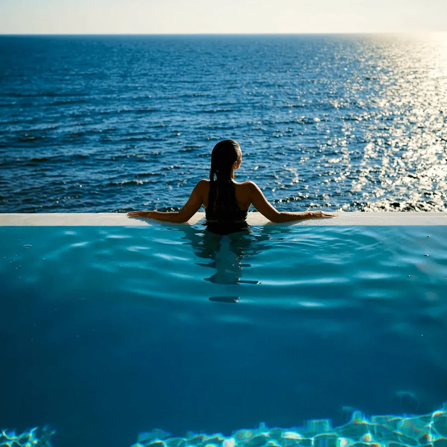 A woman in an infinity pool looking out to sea