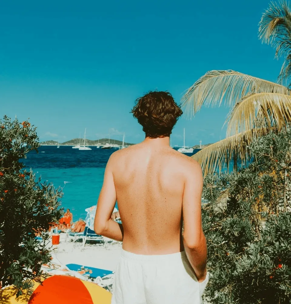 A man walking towards a beach under palm trees