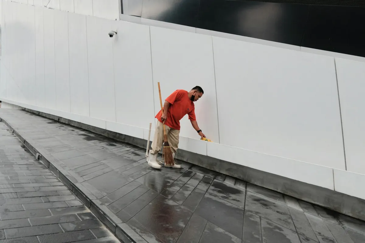 A technician cleaning the paving beside a commercial building
