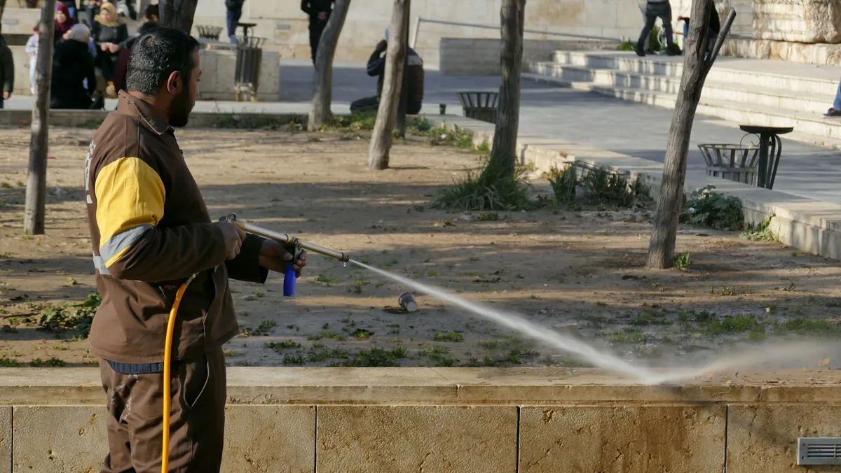 A technician pressure washing a paved driveway