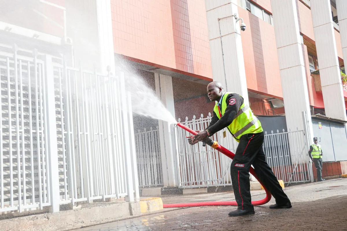 A technician pressure washing a metal fence