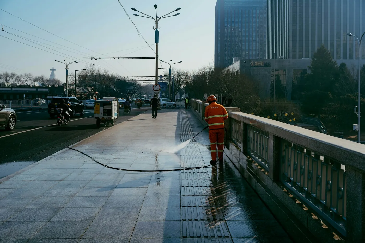Technician pressure washing a paved walkway