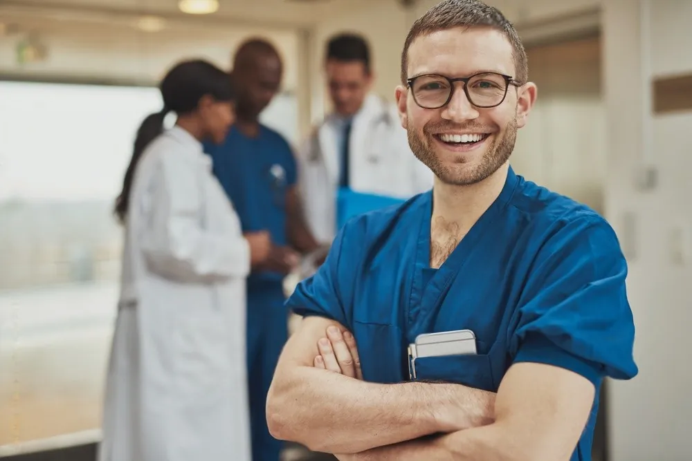 A smiling nurse with his arms crossed