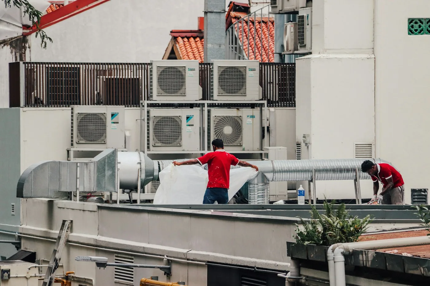 Technicians fitting a new air conditioning unit on a flat roof